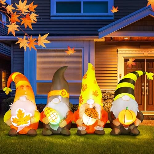 Four gnome decorations holding autumn-themed items in front of a house.