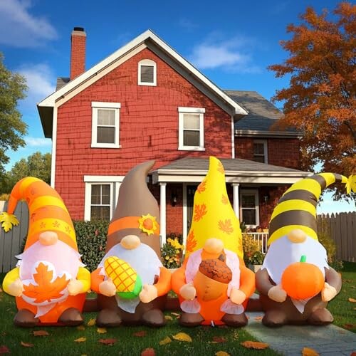 Four autumn-themed gnomes in front of a red house.