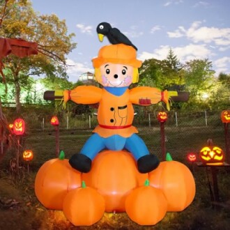 Inflatable scarecrow on pumpkins with jack-o'-lanterns.