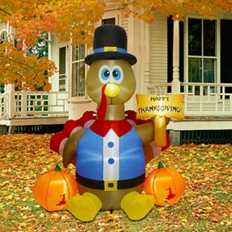 Inflatable Thanksgiving turkey decoration with pumpkins in front of a house.