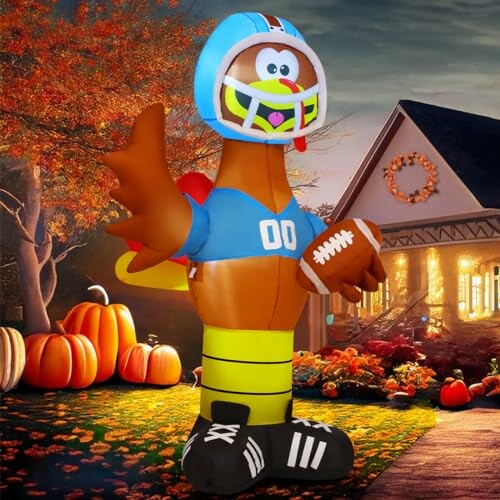 Inflatable turkey in football gear with pumpkins and house.